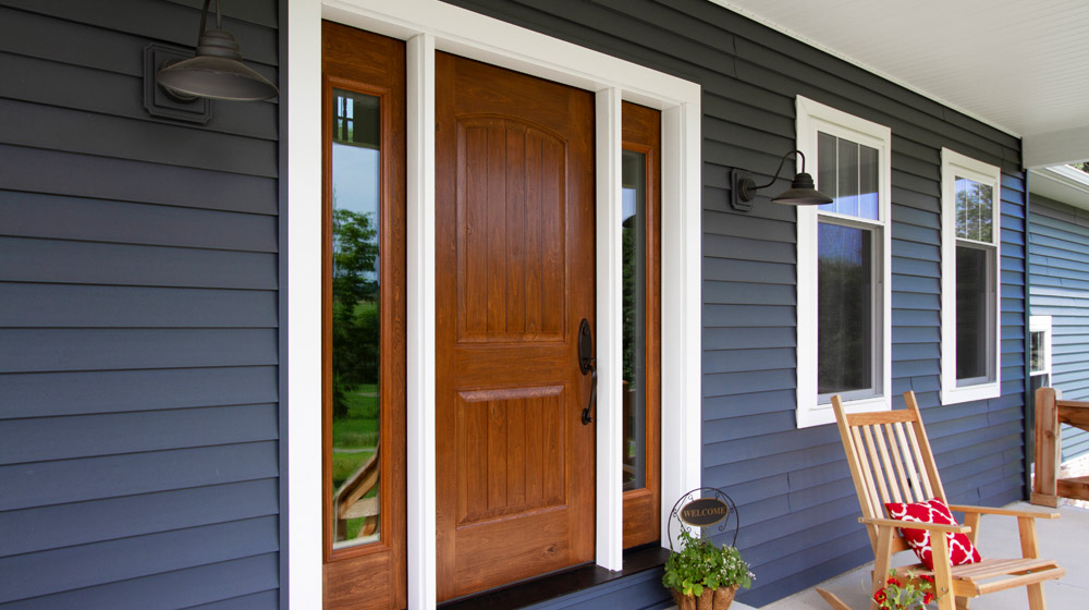 Modern blue house with large windows at dusk.