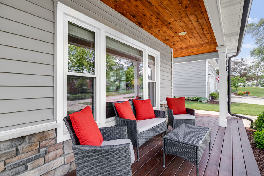 Modern porch with red-cushioned seating and wooden ceiling.