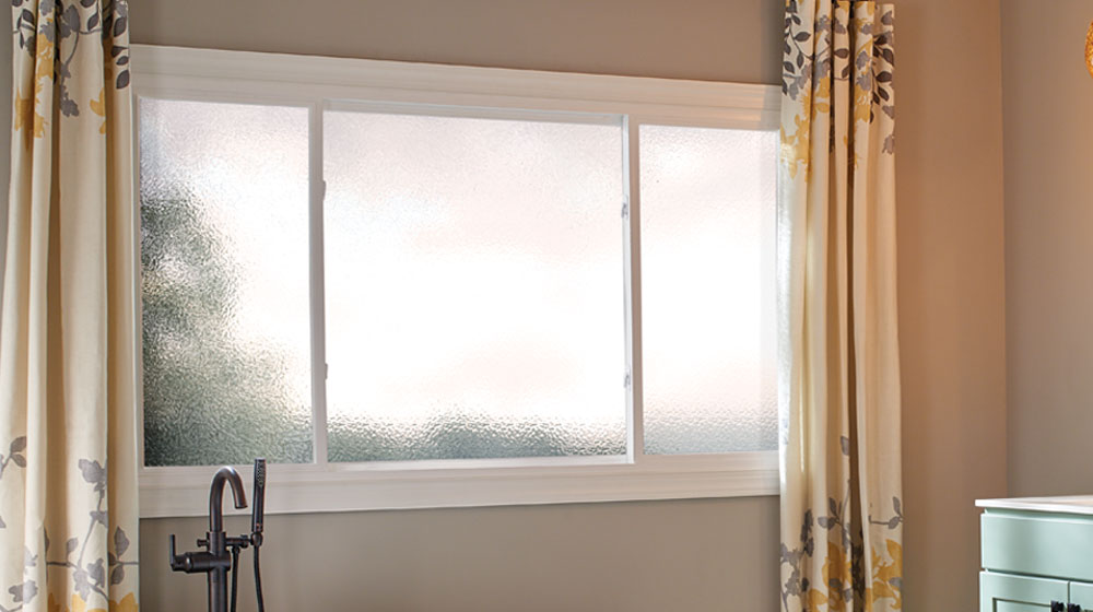 Modern blue house with large windows at dusk.