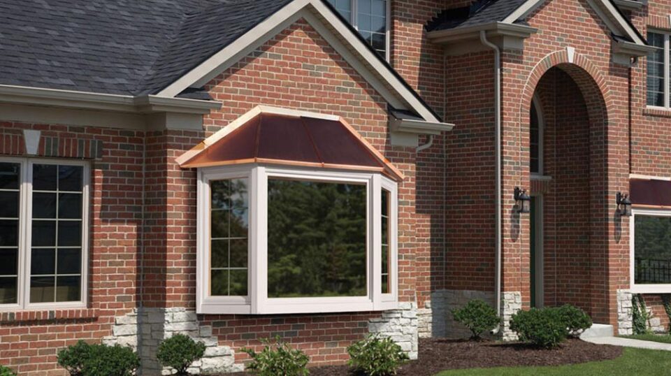 Brick house with bay window and copper roof.