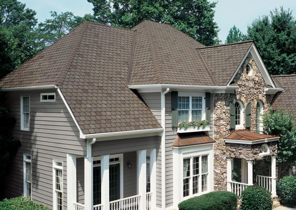 Brown shingle roof on two-story house with stone facade.