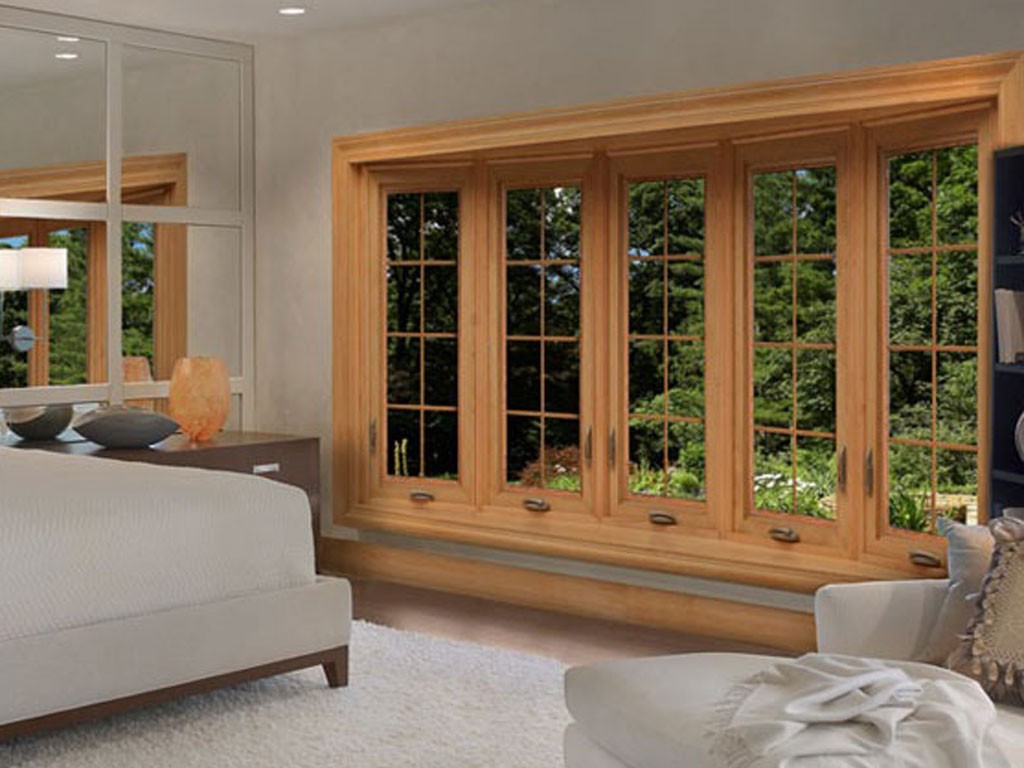Elegant bedroom with large wooden-framed windows and greenery.