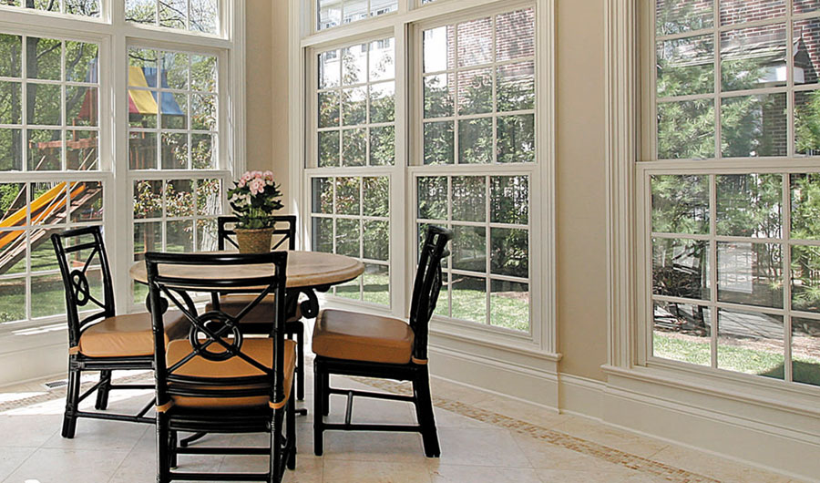 Sunlit dining area with large windows and chairs.